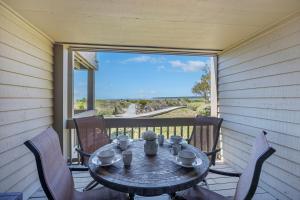 a table and chairs on a porch with a view of the ocean at 1395 Pelican Watch in Seabrook Island