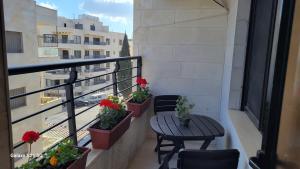 a balcony with three chairs and a table and flowers at #302 brand new two large bedrooms in Rujm ash Sharāʼirah