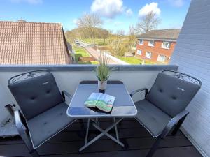 a small table and two chairs on a balcony at Wattenküste in Büsumer Deichhausen
