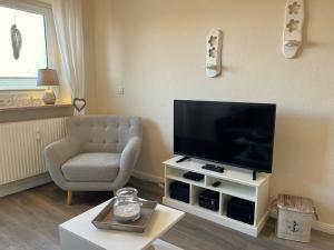 a living room with a television and a chair at Wattenküste in Büsumer Deichhausen