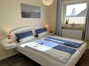 a bedroom with a bed with blue pillows and a window at Wattenküste in Büsumer Deichhausen