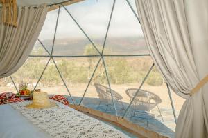 a room with a large window with a table and chairs at Ksar Shama - Atlas Mountain Retreat in Ouirgane