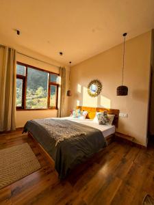 a bedroom with a large bed and a large window at Grham Hostel & Cafe Kasol, Katagla in Kasol