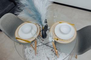 a glass table with two plates and feathers on it at Chanty Serenity- workstation, gym, backup power &Pool in Sandton