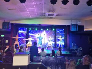 a group of people watching performers on a stage at Haggerston Castle Towerlawn 50 in Cheswick