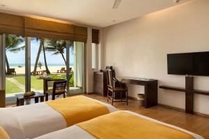 a hotel room with two beds and a flat screen tv at Jetwing Sea in Negombo