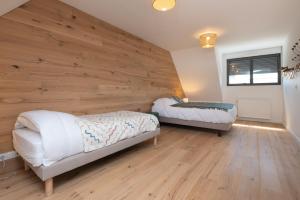 two beds in a room with a wooden wall at Maison Desmathi in Saint-Pierre-Quiberon