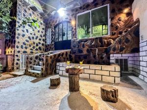 a room with a stone wall with a table and two logs at Iqama Al-Nakhlah in Ghardaïa