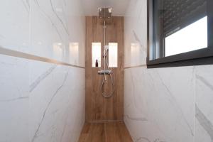a bathroom with a shower with white marble walls at Maison Desmathi in Saint-Pierre-Quiberon +24 photos