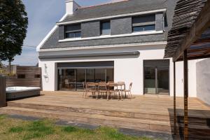 a deck with chairs and tables on a house at Maison Desmathi in Saint-Pierre-Quiberon