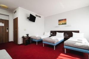 a hotel room with two beds and a tv at Focus Hotel Gdańsk in Gdańsk