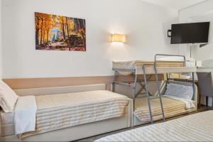 a small room with two bunk beds and a tv at Hotel Regina in Bolzano