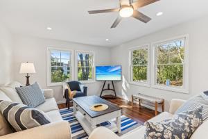 a living room with white furniture and a ceiling fan at Steps to Beach + Sunset Views! East Marion Home in East Marion