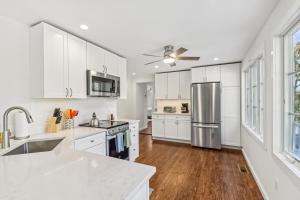 a kitchen with white cabinets and a stainless steel refrigerator at Steps to Beach + Sunset Views! East Marion Home in East Marion