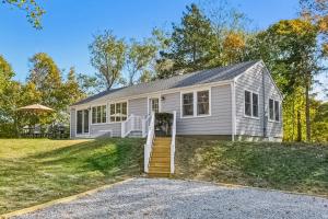 a white house with a staircase in front of it at Steps to Beach + Sunset Views! East Marion Home in East Marion