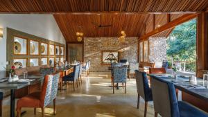 a restaurant with tables and chairs and a stone wall at Hemingways Retreat Kigali in Kigali