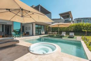 a swimming pool with an umbrella and chairs and tables at Bright villa w pool & outdoor grill u303 in Barú