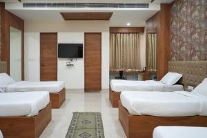 a room with four beds and a tv at Lotus Resort in Raipur
