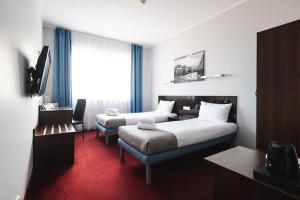a hotel room with two beds and a desk and a tv at Focus Hotel Gdańsk in Gdańsk