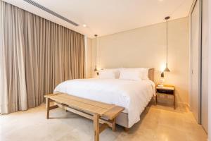 a bedroom with a large white bed and a bench at Coastal villa w dock access & pools u401 in Barú