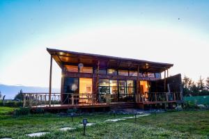 a small house with a large deck in a field at 2BR Forest Cabin, Jacuzzi, Fireplace & Mt Kenya Views in Naro Moru