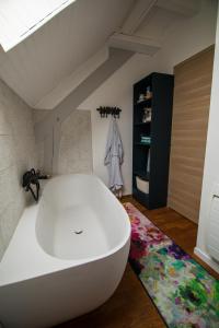 a large white bath tub in a room with a rug at Le nid du Curtil - Chambre d'hôtes in Rougegoutte +36 photos