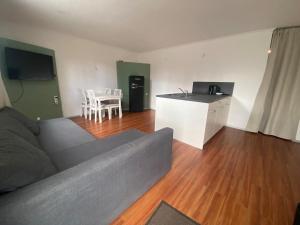 a living room with a gray couch and a kitchen at Ferienwohnung Habichtsnest in Runkel