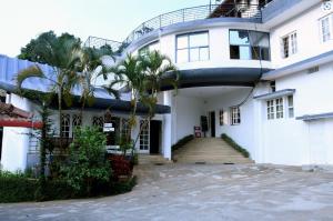 a white house with palm trees in front of it at The Lantana Resorts in Madikeri