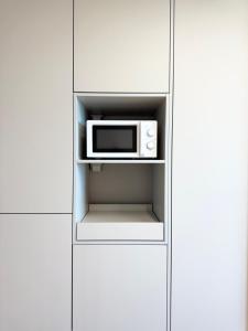 a microwave oven sitting inside of a white cabinet at Yangyang Surfing Beach 18 in Saetchak
