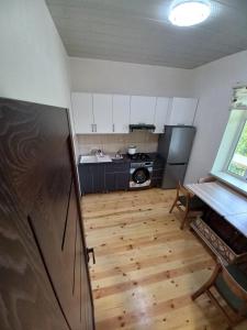 a kitchen with white cabinets and a wooden floor at Naz in Lerik