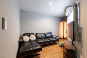 a living room with a leather couch and a flat screen tv at 翡翠名古屋本陣 in Nagoya