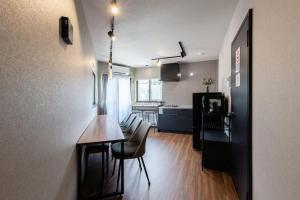 a room with a table and chairs and a kitchen at 翡翠名古屋本陣 in Nagoya