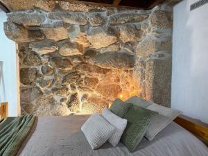 a bedroom with a stone wall and a bed with pillows at Casa do Oliveira - Gerês in Terras de Bouro