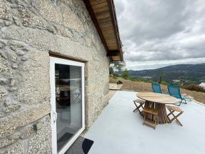 a stone building with a table and chairs on a patio at Casa do Oliveira - Gerês in Terras de Bouro