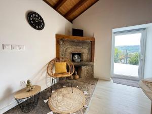 a room with a fireplace and a chair and a clock at Casa do Oliveira - Gerês in Terras de Bouro