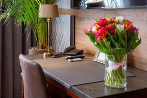 Eine Blumenvase steht auf einem Schreibtisch in der Unterkunft Hotel Golden Eagle in Levice