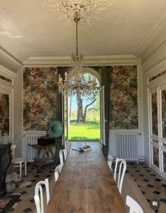 a dining room with a large wooden table and a chandelier at Les séquoias géants in Saint-Martin-aux-Arbres