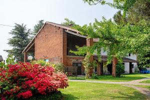 a brick house with red flowers in the yard at Cascina Brignolo - Casa Bianca in Novara