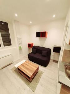 a living room with a black couch and a table at Studio 2personnes entrée autonome in La Tronche