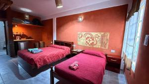 two beds in a room with red walls at Maité Hospedaje in Santa María