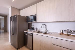 a kitchen with a stainless steel refrigerator and a sink at Oceanview 3br condo w spa & gym u603 in Barú
