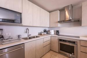 a kitchen with wooden cabinets and stainless steel appliances at Oceanview 3br condo w spa & gym u603 in Barú +42 photos