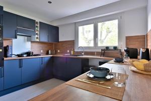 a kitchen with blue cabinets and a table with a bowl on it at Le pacifique in Schiltigheim