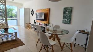 a dining room with a glass table and white chairs at Bahía Grande Nordelta - con Cochera in Benavídez