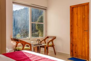 a bedroom with a table and chairs and a window at Vamitag Inn in Shimla