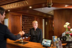 a woman shaking hands with a man at a bar at Hotel Kaiserhof Eisenach in Eisenach
