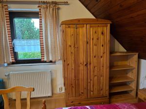 a bedroom with a wooden cabinet and a window at Appartment Sylvia von Skwarczinsky in Tabarz