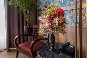 Eine Blumenvase auf einem Tisch mit einem Telefon in der Unterkunft Hotel Golden Eagle in Levice