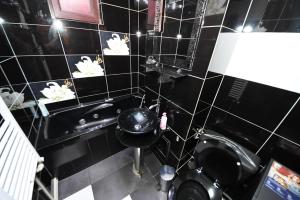 a black tiled bathroom with a toilet and a sink at Ket Apartments in Galaţi