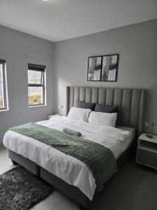 a bedroom with a large bed with a green blanket at WeThusiCBD in Mbabane